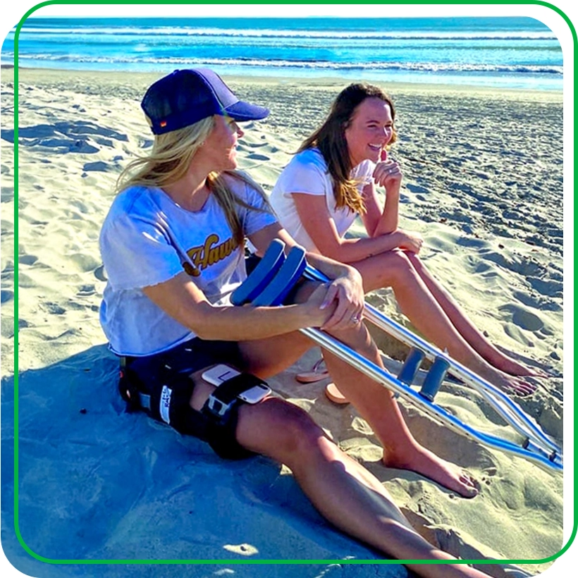 Leah Schulze wearing brace sits on beach with friend