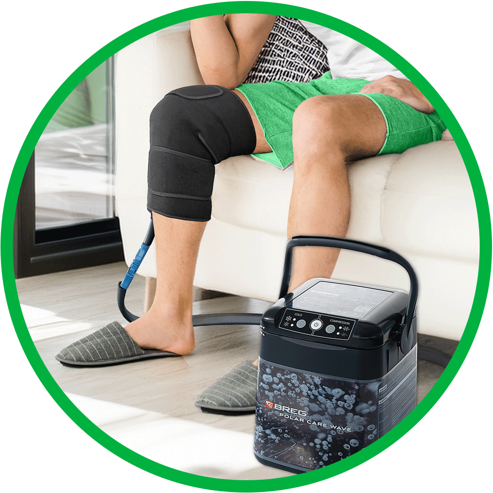 Man sits on couch using Polar Care Wave® cold therapy device on his knee